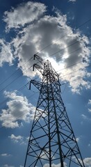 Tower against blue sky with sun and clouds illuminating power lines