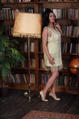 Portrait of young curly woman in yellow dress in the library full length