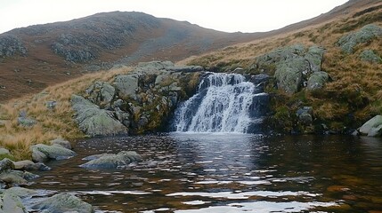 A small mountain waterfall flows into a serene reflective pond