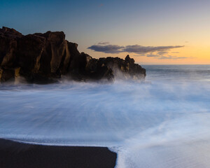 Sunset over the rocky coastline of Madeira with waves crashing on the shore