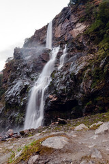 Obraz premium Waterfall among the himalaya mountains with green forest and a river full of rocks.