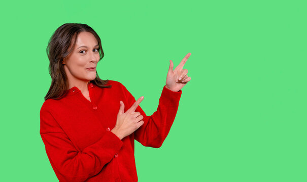 Cheerful woman in red shirt gestures with enthusiasm against a bright green background while encouraging viewers to take action