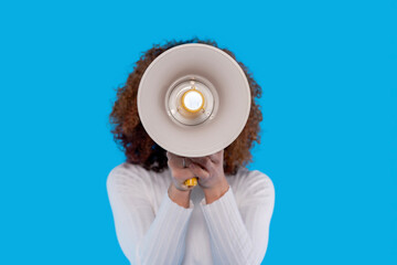 Woman holding megaphone in front of bright blue background during  public speaking event in an...