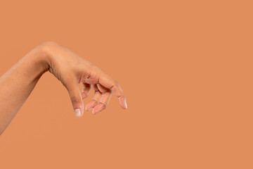 Hand gracefully extended against a warm brown background showcasing delicate fingers in relaxed...