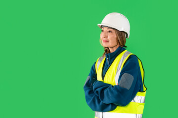 Confident construction worker in safety gear standing against green backdrop during workday, showcasing commitment to safety and professionalism
