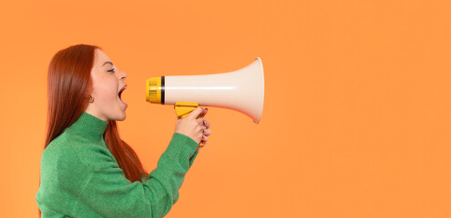 Young woman enthusiastically speaking into a megaphone against a vibrant orange background while wearing a green sweater