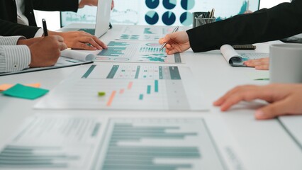 A group of business professionals collaborates during a meeting, analyzing diverse financial charts and reports while utilizing modern technology in a sleek office setting. SACTR