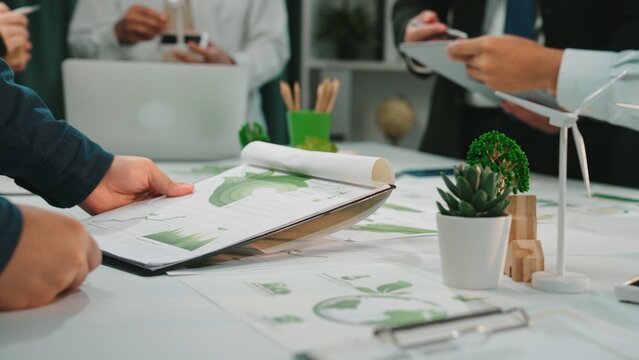 Engaging scene of a business meeting focusing on financial reports and sustainability strategies, showcasing teamwork and collaboration in a modern workspace. SACTR
