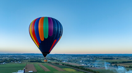 Colorful Hot Air Balloon Floats Over Countryside at Dusk Presenting Serene Aerial Views