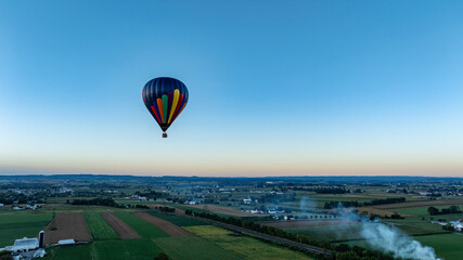 Colorful Hot Air Balloon Floats Over Countryside at Dusk Presenting Serene Aerial Views