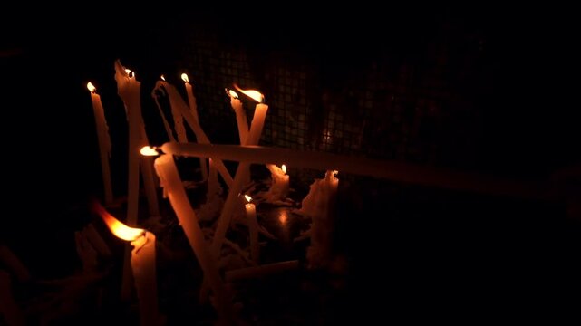 Close-up of multiple prayer candles melting in low light inside Notre-Dame de la Garde, Marseille, symbolizing faith, remembrance, and devotion within a sacred Catholic setting.