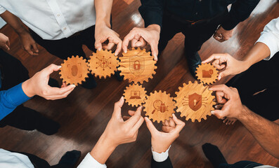 A diverse business team showcases their collective efforts in security strategies by holding wooden gears, symbolizing collaboration and innovation within corporate environments. Amity