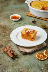 Sliced ​​finnish carrot casserole with rice and crispy crumble on top on white plate on green concrete background. Traditional food of finns at christmas.