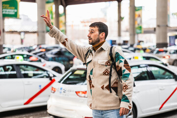 Tourist hailing a taxi in madrid atocha station, waving for transportation © Jordi Mora