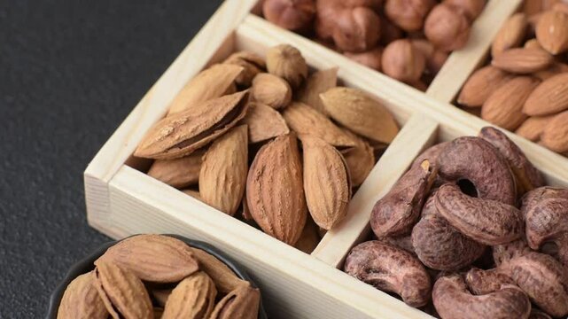 Wooden box with four sections filled with nuts almonds, shelled almonds, cashews, hazelnuts