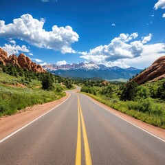 Naklejka premium A scenic view of a winding road surrounded by lush greenery and majestic mountains under a clear blue sky, perfect for travel promotions, outdoor adventures, or nature-themed designs,