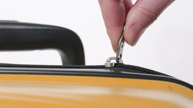 Man zipping up yellow travel suitcase close-up. Process of closing zipper on luggage.