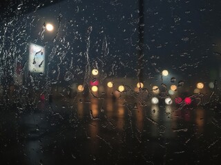 Obraz premium Rain-streaked window, condensation, steamy night, urban, reflection, winter