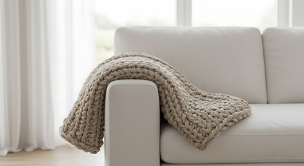 Cozy chunky knit blanket draped over a modern sofa in a minimalist living room, suitable for home decor, interior design, and lifestyle publications