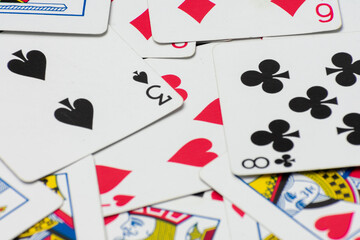 Scattered collection of playing cards, featuring various suits, numbers, and partial card faces. Chaotic arrangement creates a dynamic scene, symbolizing the unpredictability and thrill of card games