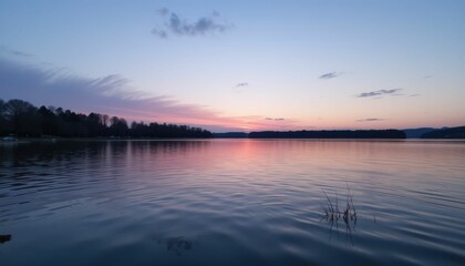 Obraz premium Tranquil Sunset Over Calm Water Reflecting Warm Colors in Sky