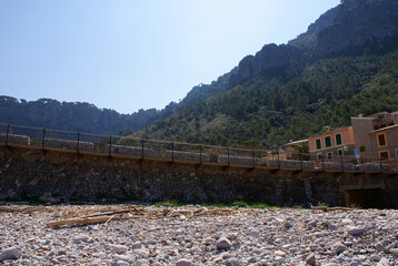 Port de Valldemossa rocky beach with rustic stone bridge, Serra de Tramuntana mountains, nature, mediterranean houses, Mallorca, Balearic Islands. Picturesque, tranquil atmosphere, scenic coastal view