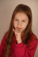Fototapeta premium The pose highlights her serenity. The little girl rests her chin on her clenched fist, looking relaxed and calm. Her expression conveys a sense of ease as she takes a peaceful moment.