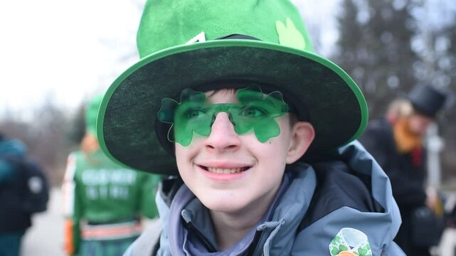 Portrait of a 12 year old boy wearing a green hat and shamrock glasses on St. Patrick's Day.