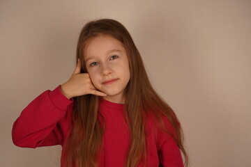 Her playful expression shows she's fully immersed in the imaginative game. A cute and fun moment of childlike creativity. The little girl holds her hand to her ear, pretending to make a phone call.