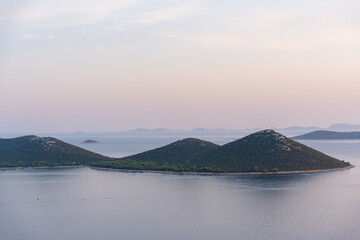 Scenic view of small green islands surrounded by calm sea waters at sunset. Concept of nature, travel, and tranquility.