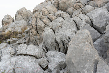Close-up view of rugged gray rocks with deep cracks and rough texture in a mountainous landscape. Concept of geology, erosion, and wilderness