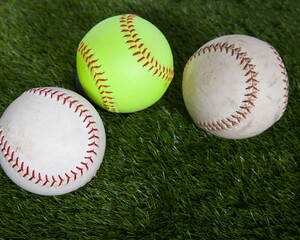 Softballs, white and yellow, on green turf
