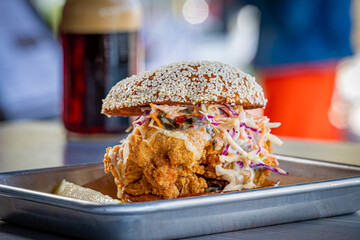 Hot Chicken Sandwich topped with Coleslaw with a dark beer.