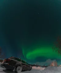 Printed kitchen splashbacks Green aurora borealis illuminating the night sky above a snow covered landscape with a station wagon parked in Swedish Lappland, creating a magical and serene winter scene