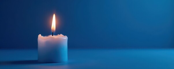 Fototapeta premium Single blue candle flame alight on blue backdrop, detail, dark blue