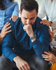 Compassionate Support Group Consoling a Distressed Man in a Bright Room