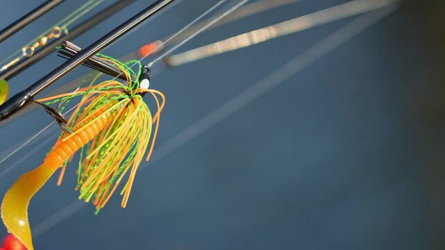 Fishing rods lines with plastic lures, selective focus, blur background. Macro close up to Jig head with paddle tail soft lures worm and Perch shad swimbait Minnow. Slow motion movement on the wind.
