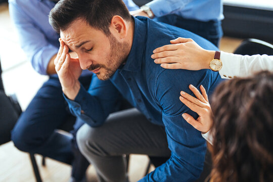 Man in Emotional Distress Comforted Supportively by Group Members in a Counseling Session