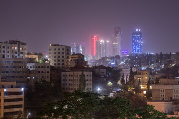 Fototapeta premium Night panorama of Amman city downtown streets with neon glowing skyscrapers, Kingdom of Jordan