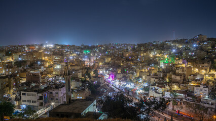 Fototapeta premium Night panorama of Amman city downtown with lots of glowing streets and highlighted houses, Kingdom of Jordan
