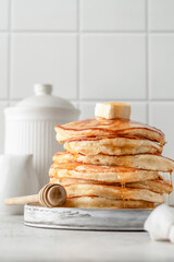 Homemade pancakes with honey an butter on top on white kitchen table background. Pancake day traditional meal