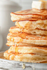 Homemade pancakes with honey an butter on top on white kitchen table background close up. Pancake day traditional meal