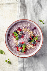 Wholegrain oatmeal porridge with blueberries, pomegranate seeds and nuts on linen tablecloth, healthy food for breakfast