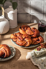 Fesh baked brioche jam swirl buns on brown kitchen table in bright morning light