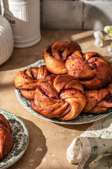 Fesh baked brioche jam swirl buns on brown kitchen table in bright morning light