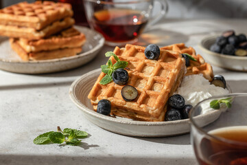 Waffles with fresh blueberries and cream in bright morning light. Healthy food, breakfast. Waffles with berries.