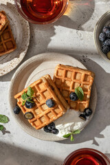 Waffles with fresh blueberries and cream in bright morning light. Healthy food, breakfast. Waffles with berries top view