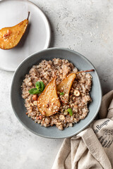 Wholegrain oatmeal porridge with caramelized pear, nuts and honey on white table, healthy food for breakfast