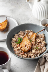 Wholegrain oatmeal porridge with caramelized pear, nuts and honey on white table, healthy food for breakfast