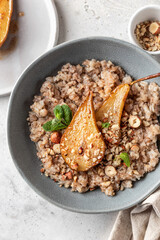 Wholegrain oatmeal porridge with caramelized pear, nuts and honey on white table close up, healthy food for breakfast